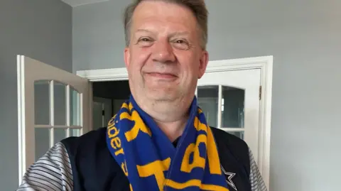 Cameron McKay Cameron McKay tiene cabello corto y castaño y se ve sonriendo. Él se para en un pasillo con un marco de puerta blanca detrás de él. Lleva un azul marino y blanco muy rayado, así como una bufanda de Bangor amarilla y azul.