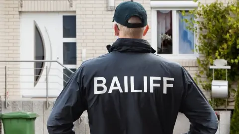 Getty Images Bailiff stands in front of house