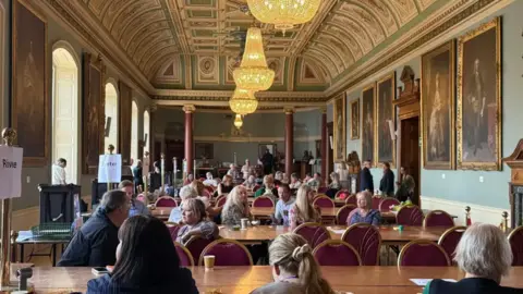 Men and women sit at several tables during the election count in Worcester.