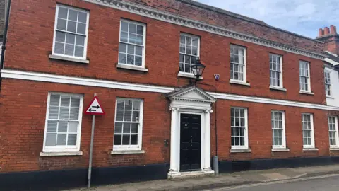 Jon Wright/BBC 19 Tower Street in Ipswich - a two story brick building with a black front door with white columns either side