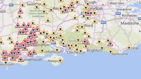 Environment Agency Environment Agency map with lots of red and orange flood warning triangles pinpointed right across the south of England