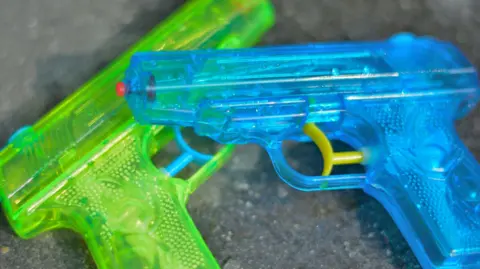 Two small water pistols - a green and blue one on a grey surface