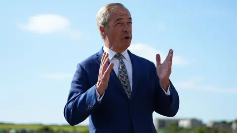 Getty Images Nigel Farage standing outside, wearing a navy blue suit and a yellow and blue tie