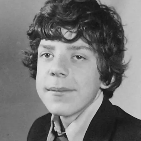 Black and white childhood photo of Mr Steele with dark curly hair wearing a school uniform