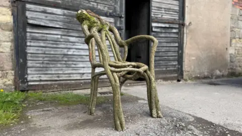 A chair grown out of tree branches sitting outside the studio of Full Grown, in Derbyshire.