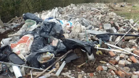 Environment Agency A large pile of rubble mixed with rubbish, like black plastic bin bags