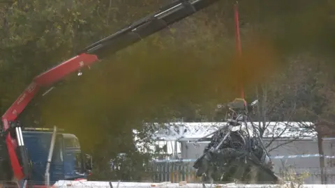 AFP Part of what remains of the helicopter which crashed outside the King Power Stadium lifted by a crane