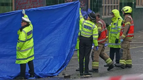 Police officers and firefighters erect tarpaulin