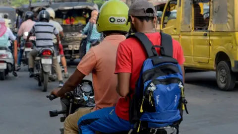 Getty Images In this photograph taken on September 12, 2019, an Ola motorcyclist transports a passenger in Amritsar.