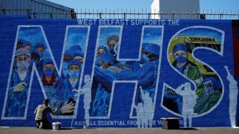 Reuters Artist Marty Lyon working on the tribute mural he and Micky Doherty (not pictured) created to honour NHS staff and key workers in west Belfast