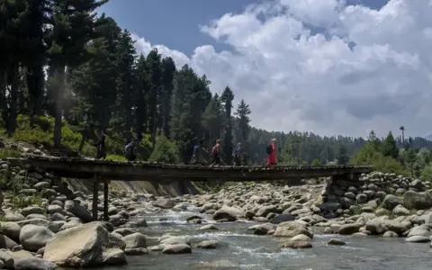 BBC Students walking to school on a bridge in Kashmir.