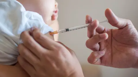 Getty Images A doctor is injecting a vaccine to a baby boy