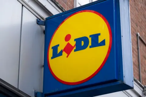 A large sign on the side of a building which reads 'Lidl' in blue and red font with a yellow circle and blue square around it. 