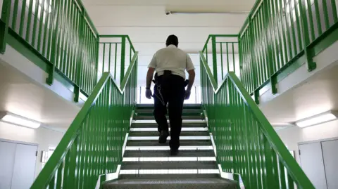 Getty Images A prison guard walks through a cell area at HMP Berwyn