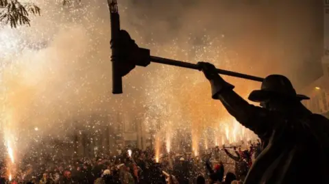 BRIDGWATER GUY FAWKES CARNIVAL A long row of squibbers at Bridgwater lighting fireworks