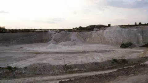 Rob Hinkley/Geograph The large, open quarry in Codicote, pictured as the light fades. It has large walls of gravel surrounding a flat pit.