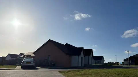 BBC Weather Watcher Ed A bright blue sky with bright sunshine in a residential street.