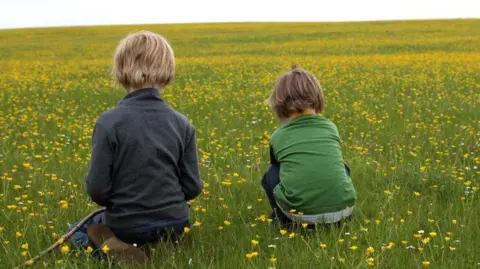 Getty Images Two children sitting in a field