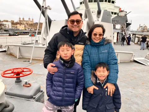 Lawrence Fong and his family stand in front of HMS Belfast