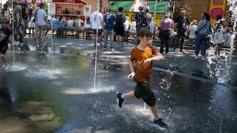 Getty Images A child runs through a water fountain to cool off in Leicester Square in London, England on 11 July 2025.