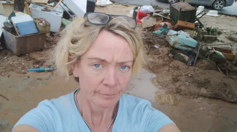 A "selfie" taken by Anabelle Reece outside with mud, puddles and piles of debris behind her.