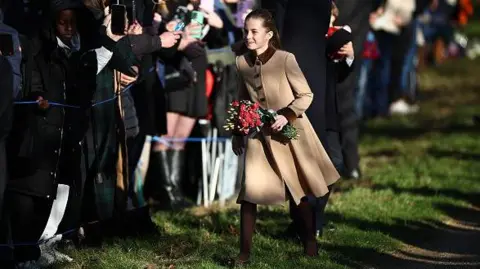 Getty Images Princess Charlotte clutches a bunch of flowers that she was gifted by a member of the public.
