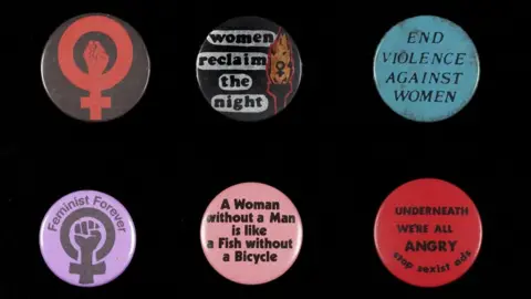 University of Leeds A selection of badges on display in the exhibition. They have slogans including "End violence against women" and "Feminist Forever".