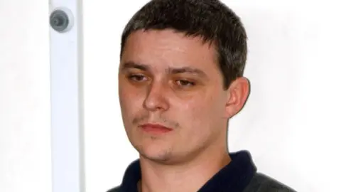 Ian Huntley pictured in 2002 outside court. He has a very faint black moustache and short black hair.