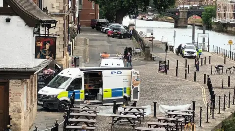 Police van and car on the riverside in York.