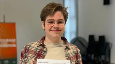 Sully smiling at the camera. He's wearing a checked shirt.