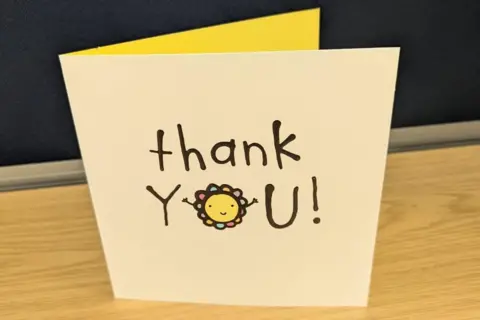 Cleveland Police Cream greetings card with the words Thanks You written on it, with a smiling flower face drawn in the "o" of the word "you"