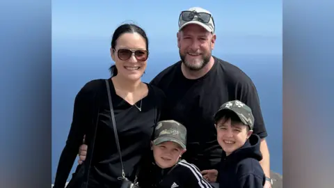 BenvsDuchenne A family photo with ben, his brother, his mum and his dad Alex. They are stood in front of an ocean.