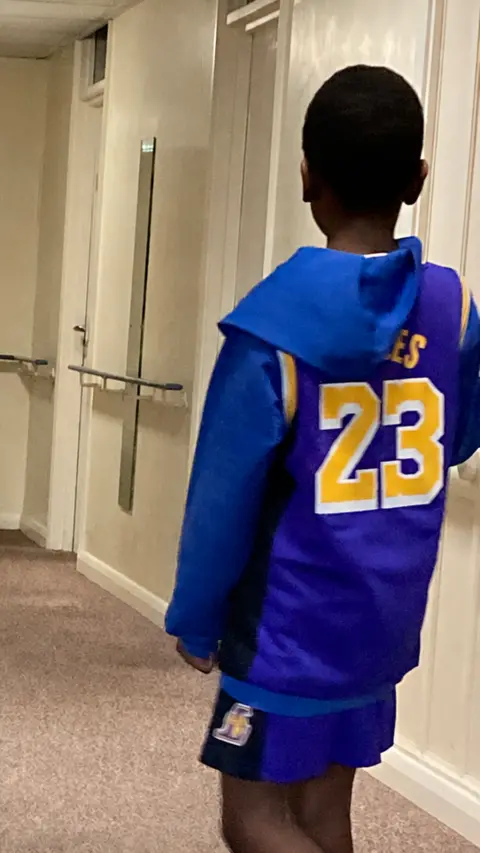 Shantel Morris A boy with his back to the camera. He is wearing a bright blue top with the number 23 on it