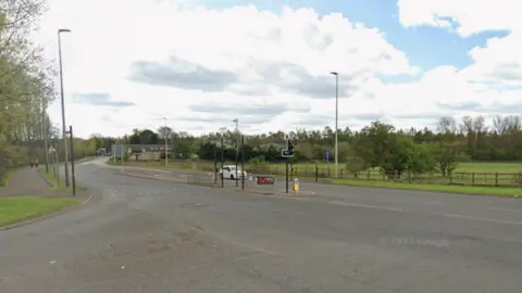 A road junction with a white car sitting at traffic lights