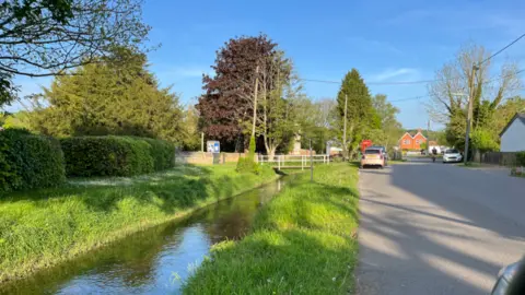 Shipton Bellinger with a small river running through it between banks of grass