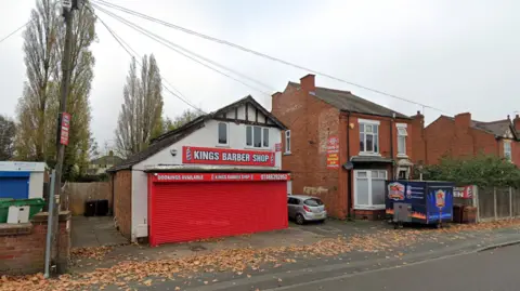 A white building with red shutters next to a red brick building