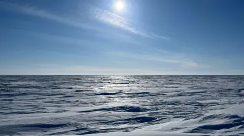 Eloise Alanna/BBC Frozen rugged terrain observed on the route from Arviat, Nunavut to Churchill, Manitoba, as BBC teams travelled on snowmobiles with the Canadian military. The sun brightly shines above the terrain, illuminating the icy ground. 