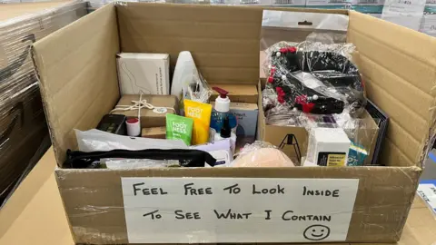 A cardboard box of items put together at the new Multibank centre in Middlesbrough to go to a family in need. It says "feel free to look inside to see what I contain" on the front.