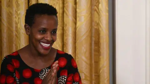 A close-up of smiling Agather Atuhaire wearing a patterned dress  