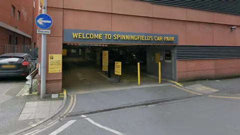 Google Street view shot of the car park. An entrance road leads into the block whilst the name of the site is spelled out in yellow capital letters.