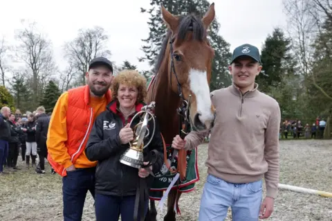 PA Media Corach Rambler with trainer Lucinda Russell and owners Cameron Sword (right) and Thomas Kendall