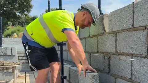 Chris Quinn laying a clay brick.