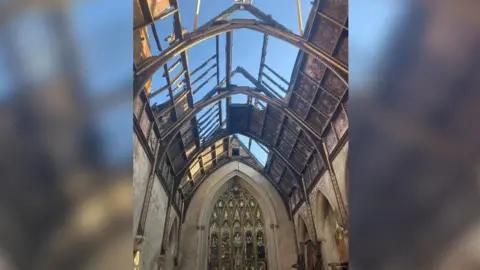 Ushaw The chapel with a stained glass window. The roof is fire damaged with large holes in it.