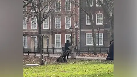 Bristol 24/7 Two people in period dress stand together in Queen Square in Bristol