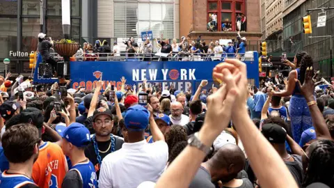 Getty Images crowd of people cheering on parade float and people hanging out of windows to watch