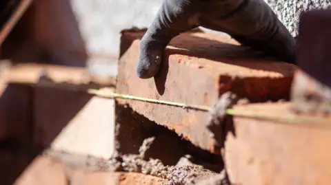 A bricklayer repairs a wall on a domestic property