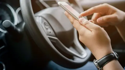 Getty Images A driver accesses the Uber app on their phone