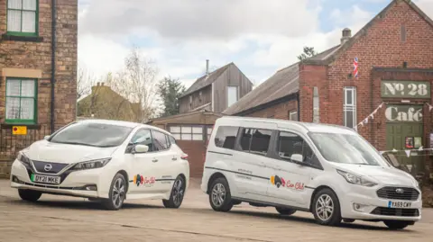 Derbyshire Community Transport One family sized car and one wheelchair friendly van in a car park with Derby Community Transport branding