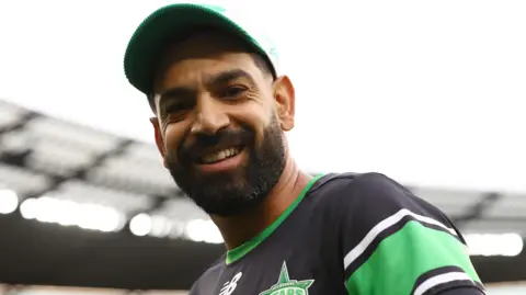 Haris Rauf wearing a cap and smiling at the camera