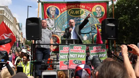 Getty Images The RMT's Mick Lynch with a microphone speaking to strikers in London in 2022